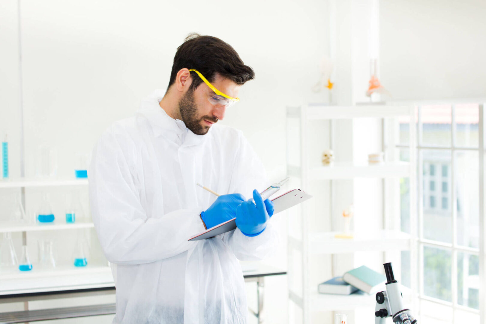 GettyImages-1251429282-copy2 A man in lab coat and blue gloves holding a tablet.