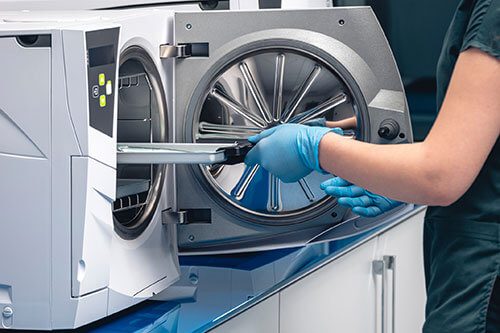 A person in gloves is opening up an empty sterile machine.