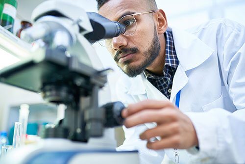 A man looking through a microscope at something